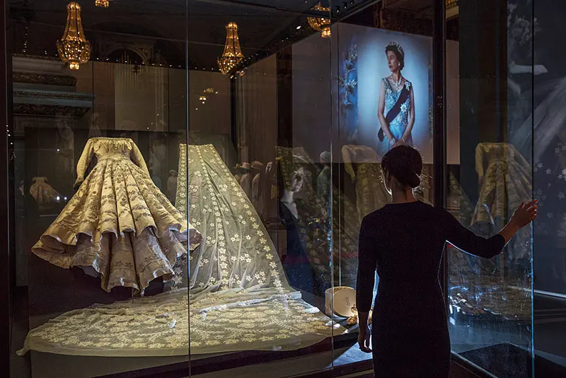A member of Buckingham Palace staff stands next to a glass case containing Queen Elizabeth II's wedding dress during a photocall at Buckingham Palace on July 21, 2016 in London, England. (Photo by Dan Kitwood/Getty Images)