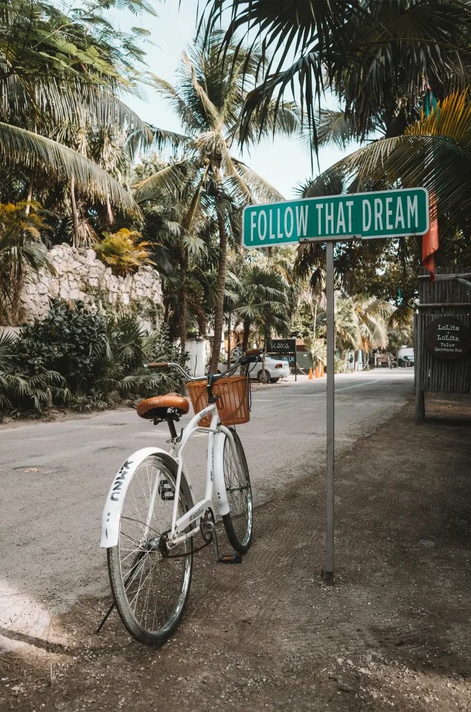 White Bicycle Parked Beside Green Signage in Quintana Roo, Mexico. Photo by Alex Azabache